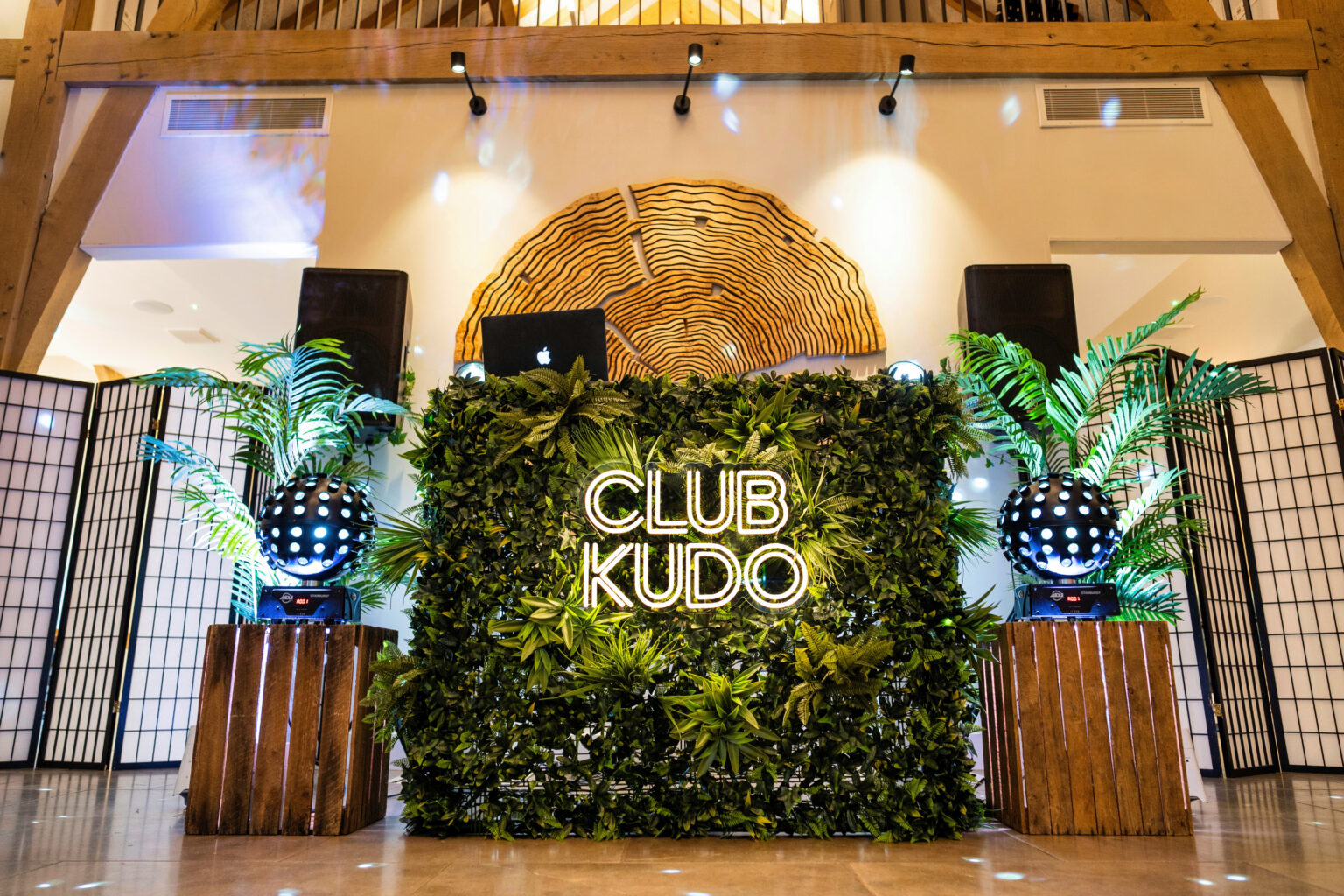 Greenery DJ booth with palm plants and foliage wall for wedding entertainment